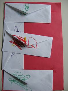 three envelopes with drawings and crayons on them sitting on top of red paper