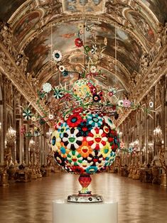 a large colorful ball sitting on top of a white pedestal in a room filled with chandeliers