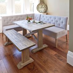 a wooden table sitting next to a white bench on top of a hard wood floor