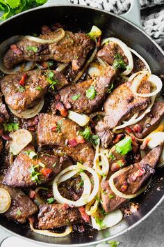 steak and onions in a skillet ready to be cooked with parsley on the side