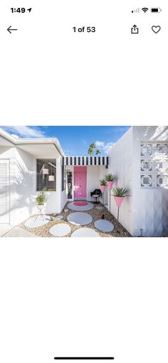 an image of a pink door in front of a white house with black and white striped awnings