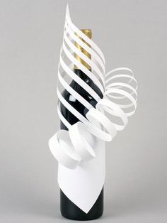 a wine bottle in a white vase with black and gold spirals on the top