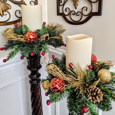 two candles are sitting next to each other on a christmas wreath with pine cones and red berries