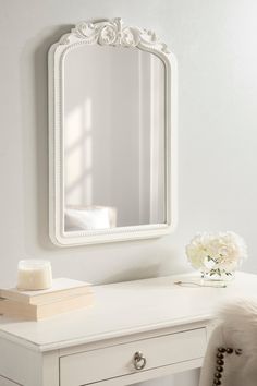 a white desk with a mirror and flowers on it