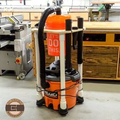 an orange and black vacuum sitting on top of a floor