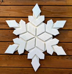 a snowflake made out of white tiles sitting on top of a wooden floor