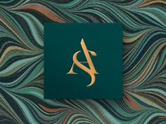 a green and gold book with the letter a on it's cover, sitting in front of a wavy background