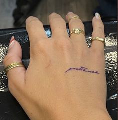 a woman's hand with a tattoo on her left wrist and the word love written in purple ink