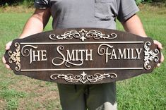 a man holding up a sign that says the smith family on it in front of some grass