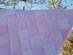 a pink and white quilt hanging from a tree