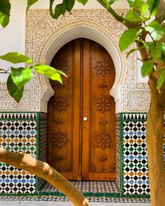 a wooden door in front of a white and green wall with tile work on it