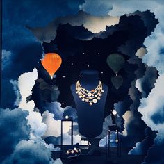 an artistic display with hot air balloons floating in the sky and clouds above it,