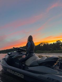 a woman sitting on top of a jet ski in the water at sunset or dawn