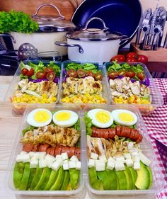 four plastic containers filled with food on top of a wooden table next to utensils