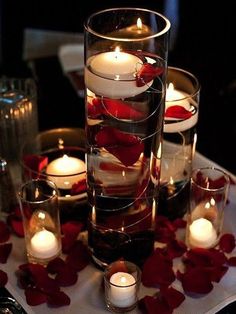 candles and rose petals are arranged in glass vases on a table with other items