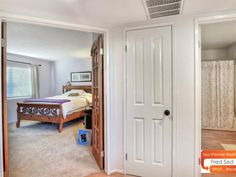 an open door leading to a bedroom with a bed in the corner and closets