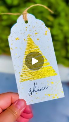 someone holding up a tag with the word shine written on it and a yellow triangle