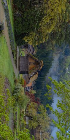 a house sitting next to a body of water surrounded by green grass and tall trees