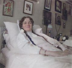 an old black and white photo of a woman laying in bed