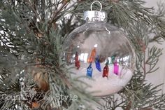 an ornament hanging from a christmas tree filled with snow and small colored candles