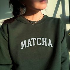 *SIZES ARE UNISEX* -I'd suggest your usual size for a more fitted look, or sizing up for a more relaxed fit. *these sweatshirts are extra comfy when oversized "MATCHA" embroidered on a comfy vintage-style crewneck. Perfect for any occasion or gift for him or her. A sturdy and warm sweatshirt bound to keep you warm in the colder months. A pre-shrunk, classic fit sweater that's made with air-jet spun yarn for a soft feel and reduced pilling. Your new favorite sweatshirt! * 50% cotton, 50% polyester * Pre-shrunk * Classic fit with no center crease * 1x1 athletic rib knit collar with spandex * Air-jet spun yarn with a soft feel and reduced pilling * Double-needle stitched collar, shoulders, armholes, cuffs, and hem * Gildan 18000 Unisex Heavyblend Sweatshirt Please note that the embroidery com Matcha Shirt, Barista Shirt, Matcha Latte, Fitted Sweater, Look Plus, Style Vintage, Vintage Stil, Matcha, Rib Knit