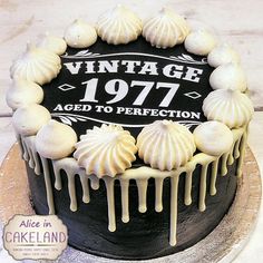 a black and white cake with icing on it's top is decorated with the words vintage 1971 aged to perfection