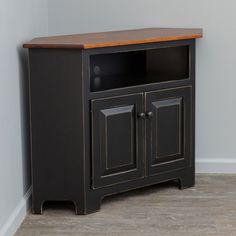 a black entertainment center with wooden top and two doors on both sides, against a gray wall