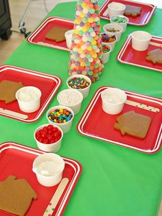 the table is set up with red trays and green tablecloth, including gingerbread cookies