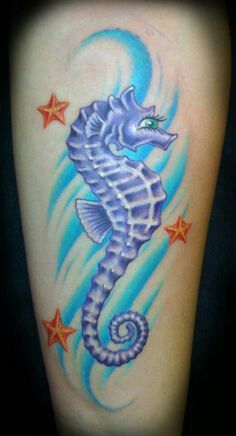 a blue seahorse with stars on its arm and the ocean is in the background