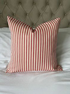 a red and white striped pillow sitting on top of a bed