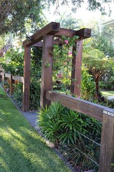 a wooden bench sitting next to a lush green field