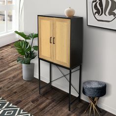 a black and yellow cabinet next to a potted plant in a room with wood floors