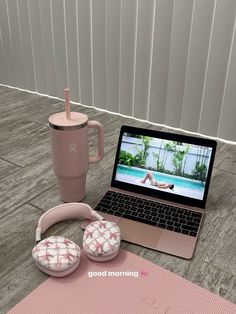 an open laptop computer sitting on top of a table next to headphones and a cup