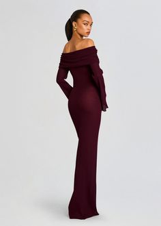 a woman wearing a long sleeved dress with an off the shoulder neckline and high slit