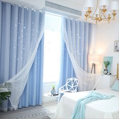 a bedroom with blue curtains and white bedding