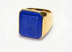 Lapis Crest Men’s Ring. Step up your style game with this exquisite vintage Men's Ring featuring a stunning Lapis Crest set in 18K gold. This eye-catching piece is perfect for those who appreciate the finer details and quality craftsmanship. The deep blue lapis lazuli is elegantly set in the warm sheen of 18K gold, providing a sophisticated touch to both casual and formal attire. Make a statement with this unique ring that combines classic elegance with modern style. Material: 18K Gold Gemstone: Lapis Lazuli Ideal for both casual and formal occasions Size 10.75 - 11. Top measurements 20 mm by 19 mm. Add this luxurious ring to your collection and enjoy the perfect blend of tradition and trend. Luxury Blue Signet Ring Collectible, Luxury Blue Antique Signet Ring, Luxury Antique Men's Signet Ring, Luxury Blue Cabochon Signet Ring, Blue Lapis Lazuli Gemstone Signet Ring, Montblanc Pen, Belt Purse, Costume Jewelry Earrings, Silver Enamel