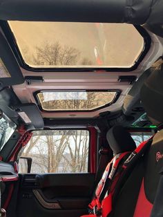 the interior of a vehicle with its sunroof open and red seats folded down