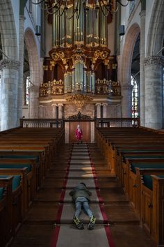 a person laying on the ground in front of a church organ with its lights on