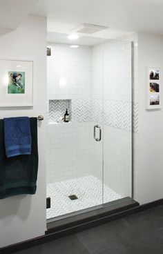 a walk in shower sitting next to a white tiled wall and black tile flooring