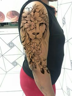 a woman's arm with a lion and flowers tattoo on her left shoulder, which is covered in black ink