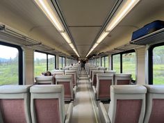 the inside of a train car with lots of seats on each side and windows open