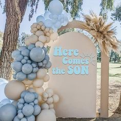 there is a sign that says here comes the son and balloons are all around it