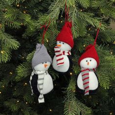 three snowman ornaments hanging from a christmas tree