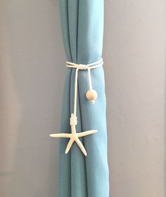 a curtain with starfish and seashells tied to it's rod ends