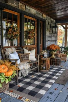 the porch is decorated for fall with pumpkins