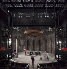 an empty stage with people sitting and standing on it in front of a circular ceiling