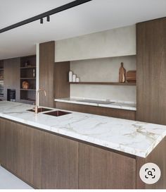 a large kitchen with marble counter tops and wooden cabinetry is featured in this image