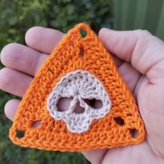 a hand holding an orange crocheted object in it's palm