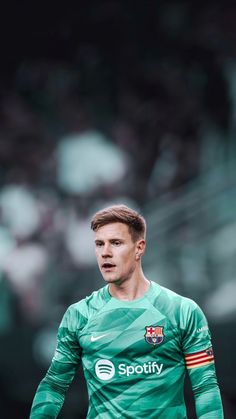 a soccer player in green uniform on the field with his head turned to look like he's about to kick the ball