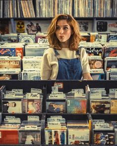 a woman standing in front of a store filled with cds